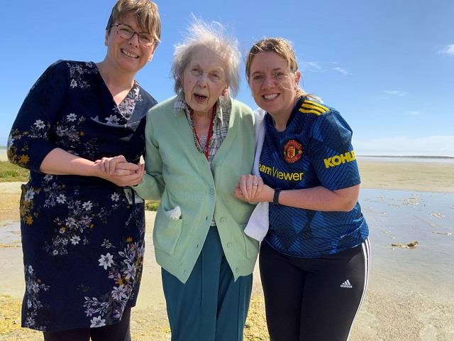 Photo of care home resident enjoying a paddle on a Sanday beach with help from our adult social care staff.