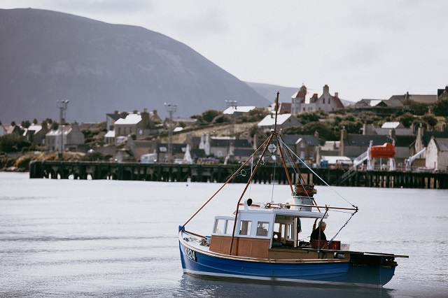 Photo of Stromness from the harbour with small vessel.